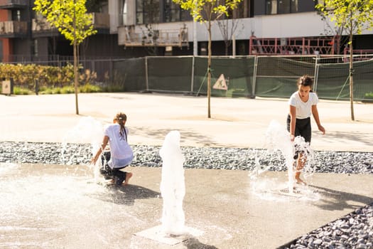 life of children in a modern city - little girl having fun with fountains. High quality photo