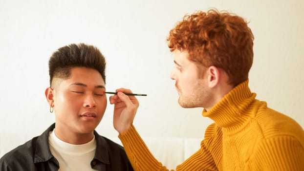 Concentrated gay man applying make up to her partner at home