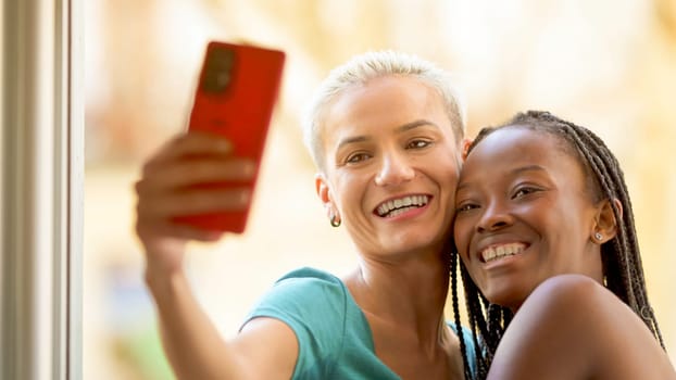 Lesbian couple taking a selfie while smiling on a balcony