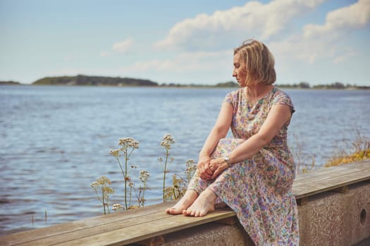 Aalborg, Denmark, July 10, 2022: Beautiful mature woman relaxing near the sea