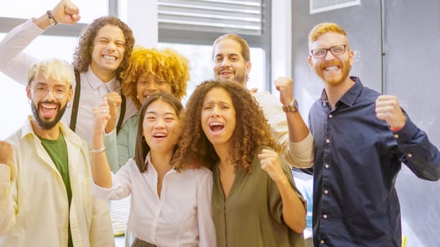 Team of coworkers celebrating raising fist and looking at camera