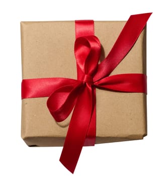 Box is wrapped in brown paper and red ribbon on a white isolated background, top view