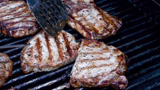 Grilled meat steak on stainless BBQ grill with flames on dark background. Food and cuisine concept