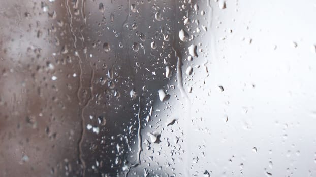 Macro of water drops on glass. Large rain drops strike window during winter shower. Pure rain drops