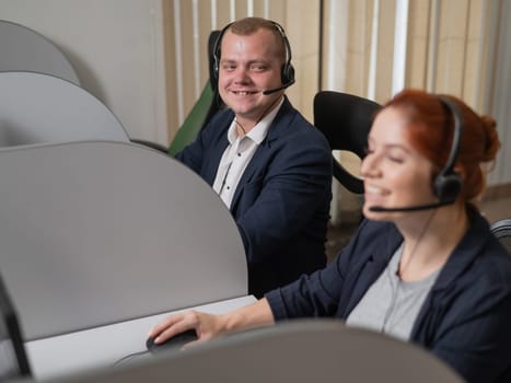 Two friendly call center employees answer customers by phone. Man and woman woman talking on a headset in the office