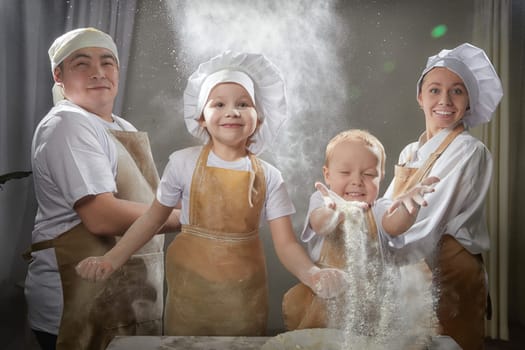 Cute oriental family with mother, father, daughter, son cooking in kitchen on Ramadan, Kurban-Bairam, Eid al-Adha. Funny family at flour cook photo shoot. Pancakes, pastries, Maslenitsa, Easter