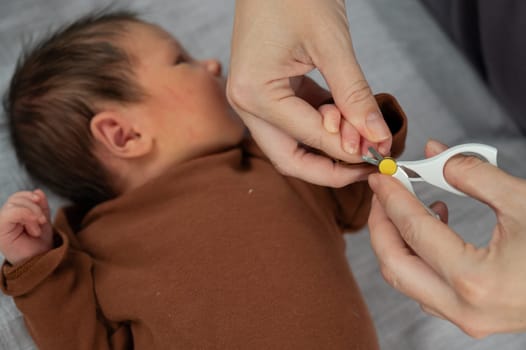 Mom cuts her newborn son's fingernails with small children's scissors