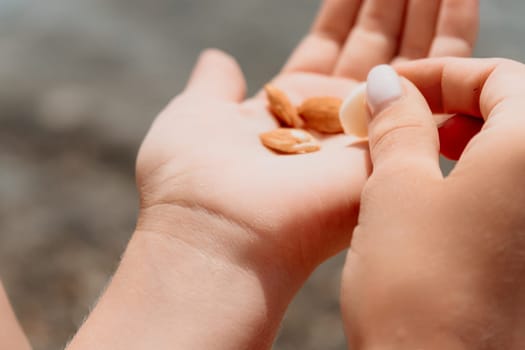 Woman eating milky almond nuts. A young caucasian woman choping fresh green almond after morning fitness yoga near sea. Only hands are visibly. Healthy vegan food. Slow motion. Close up