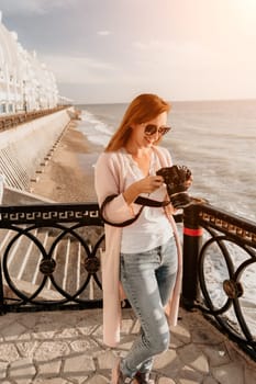 Woman travel sea. Young Happy woman in a long red dress posing on a beach near the sea on background of volcanic rocks, like in Iceland, sharing travel adventure journey