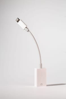 A white lightning cable made of composite material is resting on a glass table, creating a transparent and modern look