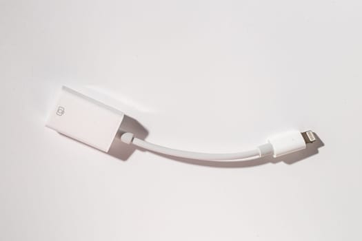 A white lightning cable made of composite material is resting on a glass table, creating a transparent and modern look