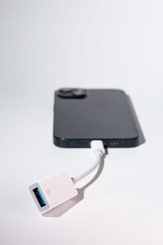 A smartphone connected to a USB adapter as a portable communication device for port-based data transfer.