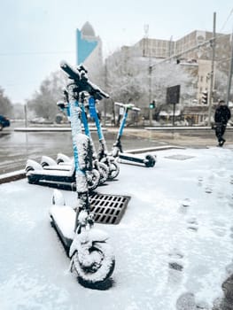 blue city scooters in the snow at the crossroads.