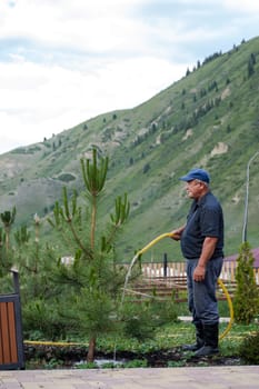 the janitor waters the garden in summer at the foot of the mountains.