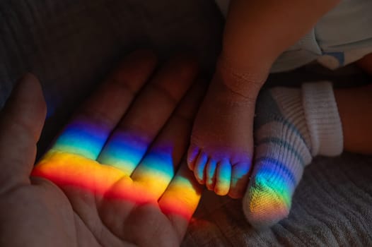 A man holds his newborn son by the leg. Beam of light through a prism