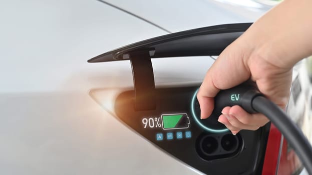 Closeup hand charging a luxury electric car with status data. Green energy sustainability concept.