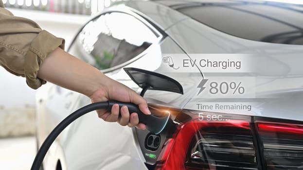 Man inserting EV charging plug to electric vehicle in the garage outside a home. Eco and clean energy concept.