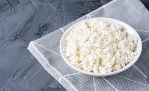 Cottage cheese in a white bowl on a grey background.