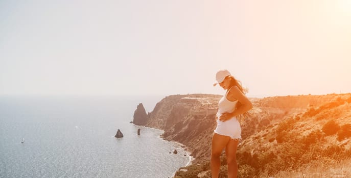 Woman travel sea. Young Happy woman in a long red dress posing on a beach near the sea on background of volcanic rocks, like in Iceland, sharing travel adventure journey