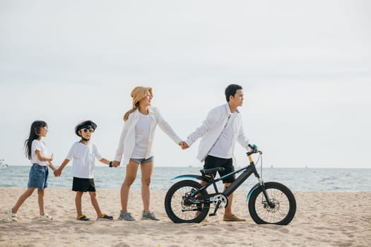 A family walk on the sandy beach parents pushing bicycles full of happiness joy and the carefree spirit of a childhood day by the sea. Family on beach vacation