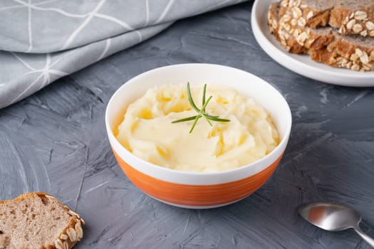 Mashed potatoes in bowl and rye bread on grey table. Healthy food.