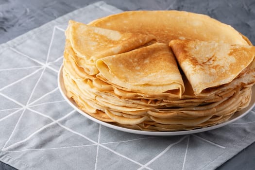 A stack of thin pancakes on a grey table , with copy space for text.