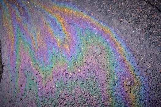 Colored oil stains close-up, color of a gasoline stain on asphalt as a texture or background.