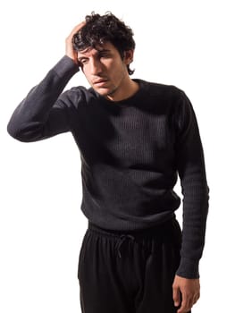 A man in a black sweater is seen holding his head with both hands, looking distressed or deep in thought.