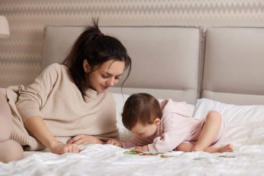 cheerful mother playing puzzle together with her little child girl in bedroom