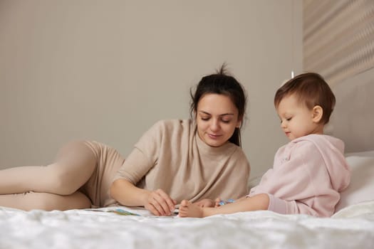 beautiful mother playing with puzzle pieces with little child girl in bedroom