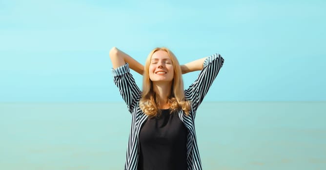 Summer vacation, happy relaxing healthy young woman meditates and enjoying fresh air on the beach on sea coast and blue sky background