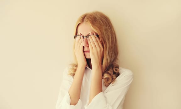Tired overworked young woman employee rubbing her eyes suffering from eye strain or headaches after working at computer. Exhausted office worker