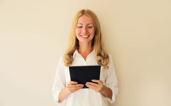 Portrait of happy smiling caucasian young woman employee with digital tablet computer or folder with documents in office