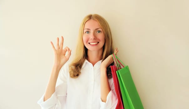 Portrait of happy smiling caucasian young woman posing with shopping bags on beige studio background