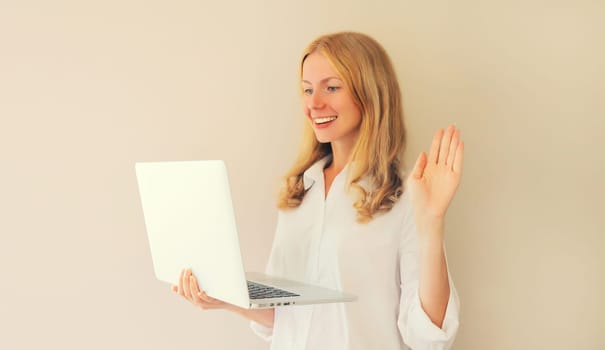 Happy smiling caucasian young woman greets communicates with friends via video call on laptop at home