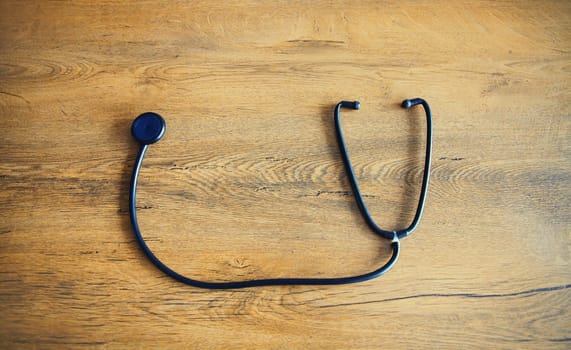 Close up medical stethoscope on wooden table, top view
