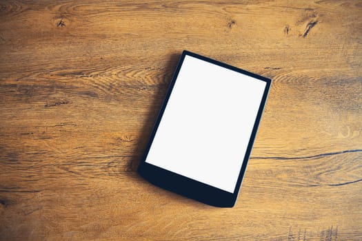 White blank screen digital tablet computer on wooden table at home, top view