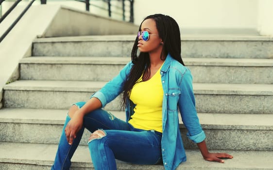 Portrait of stylish young african woman with dreadlocks posing wearing casual in the city