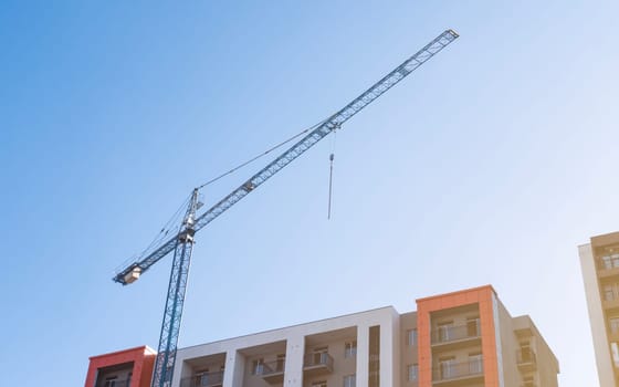 A crane is positioned in the sky above a building under construction