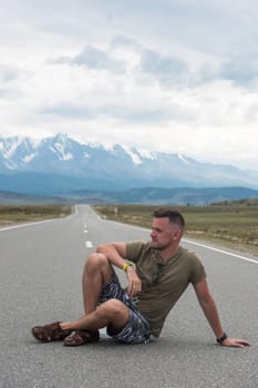 A young man sitting on the road in the Chuysky Tract area. Altai Republic, Russia.