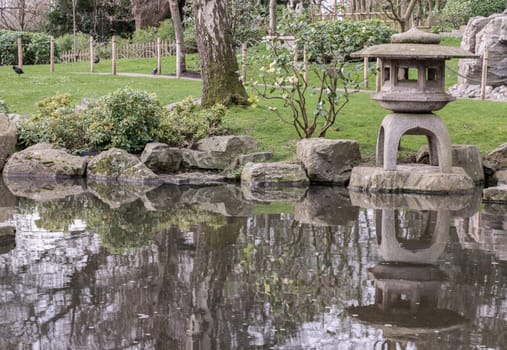 Decorative japanese stone lantern on Summer zen lake pond water.  A Japanese Garden style, Selective focus.