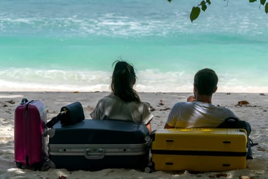 travellers with luggage relaxing on sandy beach
