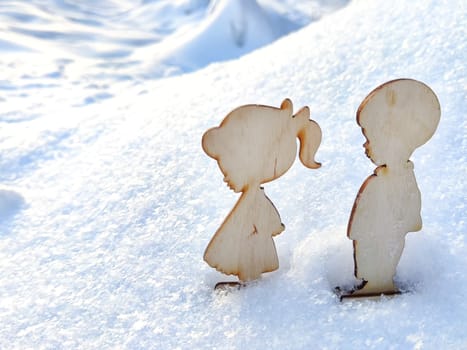 Wooden toys of boy and girl on white snow. Couple in love on Valentine's Day in February. Love in cold world. Card, background
