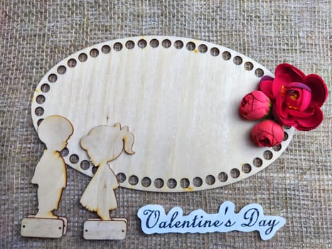 Wooden figurines of couple, inscription Valentine's Day, red flowers. Concept of holiday of love. Background, texture, frame, place for text, copy space