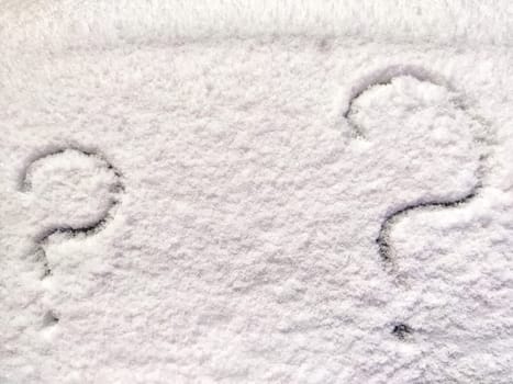 Two question marks written in snow. The cold frosty texture of the snow and the question mark. Background, place for text, copy space
