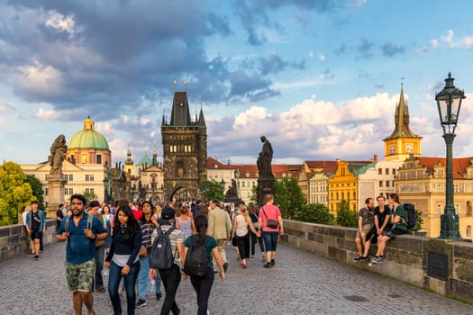 Prague, Czechia - 25 May 2018: People are walking over the famous Charles Bridge in Prague during sunny day.  View of the Lesser Bridge Tower of Charles Bridge (Karluv Most) full of tourists.