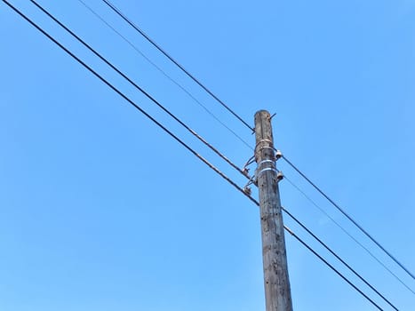 Old power line pole against blue sky in a nice sunny day