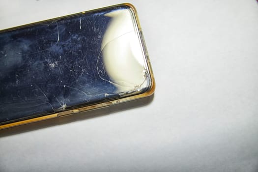 Close-Up View of a Cracked Smartphone Screen Against White Background. the detailed texture of a shattered smartphone screen, emphasizing extensive damage to the device
