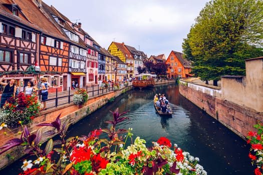 Colmar, France - July 27, 2018: Old town of Colmar, Alsace, France. View with colorful buildings, canal and flowers. Colmar, France. Petite Venice, water canal and traditional half timbered houses.