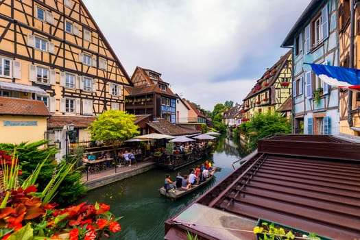 Colmar, France - July 27, 2018: Old town of Colmar, Alsace, France. View with colorful buildings, canal and flowers. Colmar, France. Petite Venice, water canal and traditional half timbered houses.